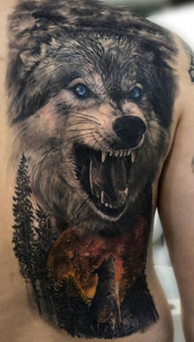 Large snarling wolf backpiece tattoo with piercing blue eyes above a wolf howling up in front of a blood moon with fir trees