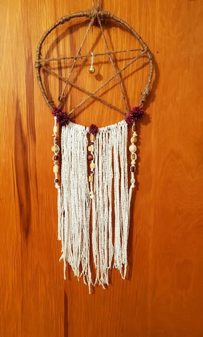 Brown string pentacle dream catcher with white hanging tassels and strings of beads.